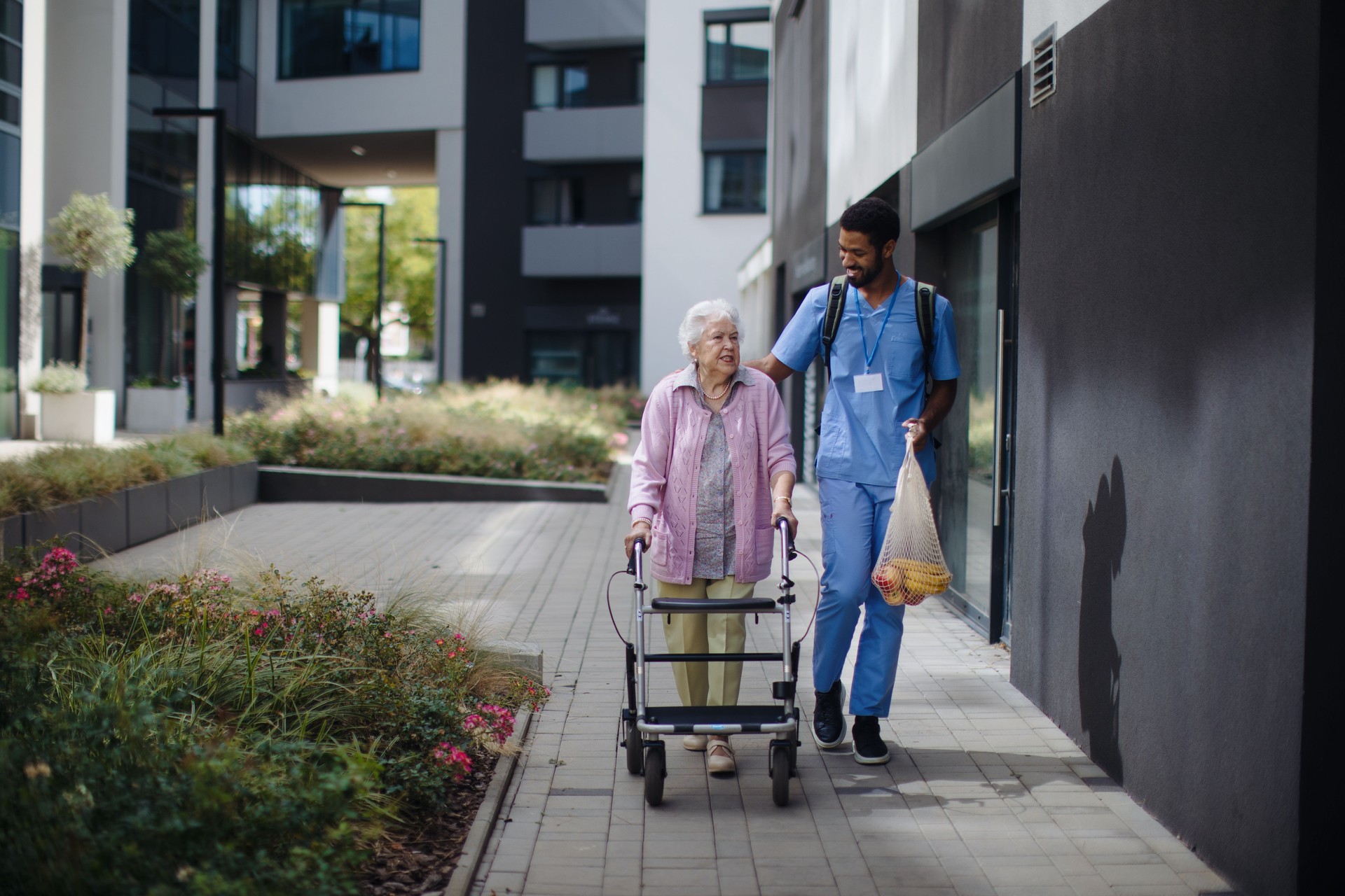 Happy caregiver caming back from grocery with his senior woman client.